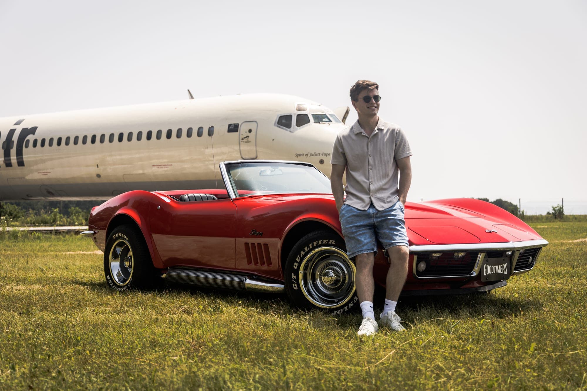 Rdeča Corvette pred trupom letala na travniku